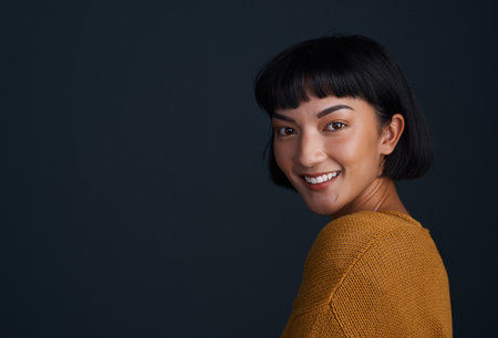 Practice confidence daily. Studio shot of an attractive young woman posing against a dark background.の写真素材