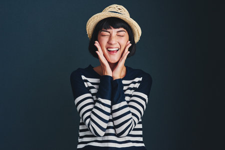 Im so excited and I just cant hide it. Studio shot of an attractive young woman against a dark background.の写真素材