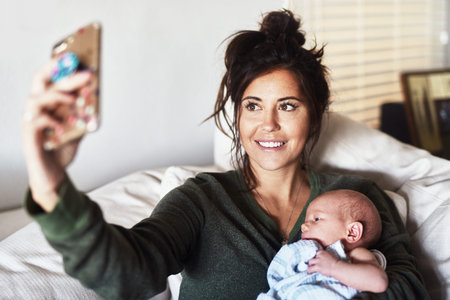 This is for the memories. a cheerful young woman lying on the sofa while holding her little infant...