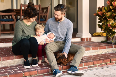 Our family is growing. a young cheerful family standing together outside at home during the day.の写真素材
