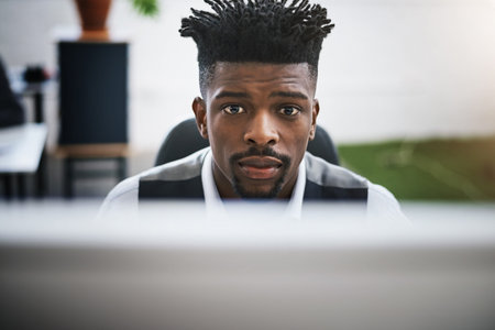 Staring the business day straight in the eye. a young businessman using a computer at his desk in a...