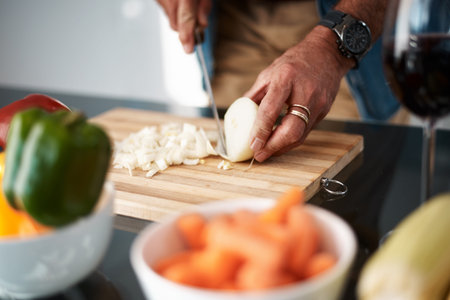Good food requires onions. an unrecognizable man chopping onions on a cutting board.