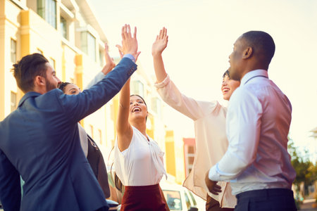 Unity is the key to unlock success. a group of businesspeople high fiving together outdoors.