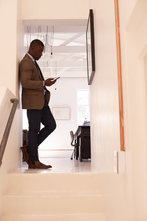 Making contact with a client. a young businessman using a cellphone in an office.の写真素材