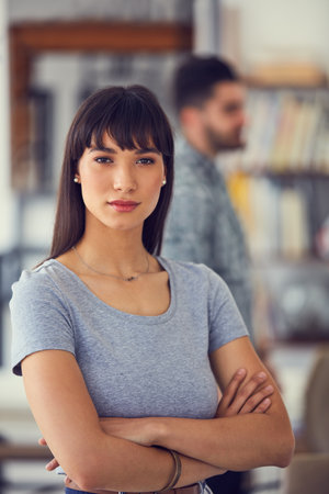 Were a small company but weve got big plans. Portrait of a confident young businesswoman with her colleagues working in the background of a modern office.の写真素材