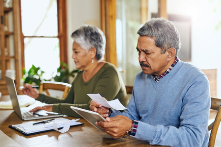 Taking care of their financial matters. a mature couple managing their paperwork together at home.の写真素材