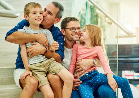 Kisses all around. an affectionate family of four on the stairs at home.の写真素材