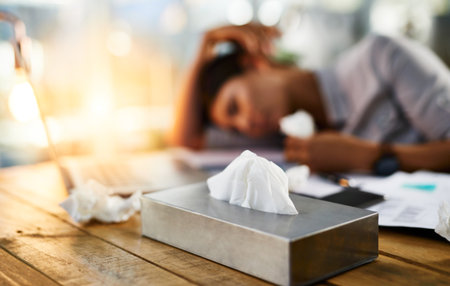 I dont think I can work today. a businesswoman working in her office while suffering from allergies.の写真素材