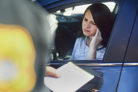 Another fine. an unrecognizable male traffic officer issuing a ticket to a female civilian at a...