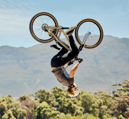 Mountain bike, man and upside down air jump, action and bicycle stunt, challenge and adventure, freedom or dynamic risk in sky. Biker athlete, sports adrenaline and energy in outdoor competition showの写真素材
