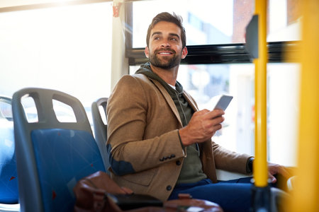 Looks like my stop. a handsome young man sending a text message during his morning bus commute.の写真素材