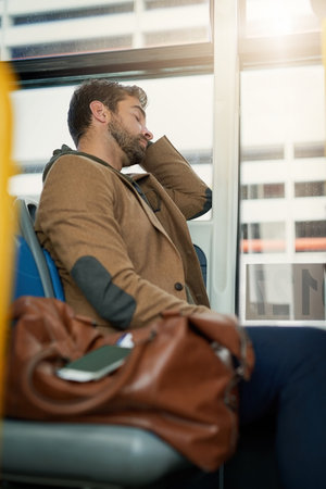 Catching some shuteye on the bus. a handsome young man sleeping on the bus during his morning commute.の写真素材