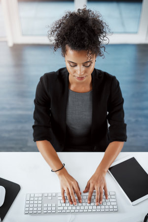 Every workday comes with brand new opportunity. High angle shot of a young businesswoman using a computer at her desk in a modern office.の写真素材