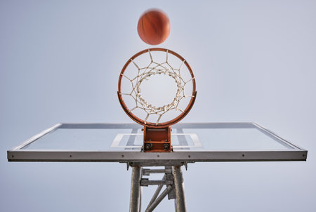 Basketball, shooting ball and target of outdoor sports goals, competition game and action on sky background. Background basketball court, air net and winning contest, training skill and performanceの写真素材