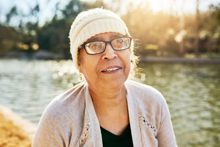 Growing older, days like these matter more. Portrait of a senior woman standing next to a lake.の写真素材