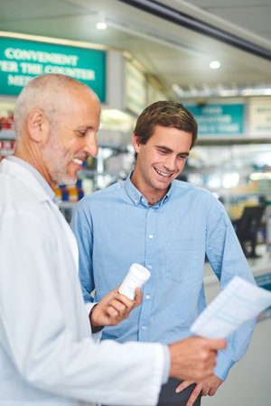 This is for you. a handsome mature male pharmacist helping a customer in the pharmacy.の写真素材