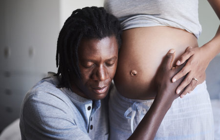 I promise to be the best dad. a man listening to his wifes pregnant belly.の写真素材
