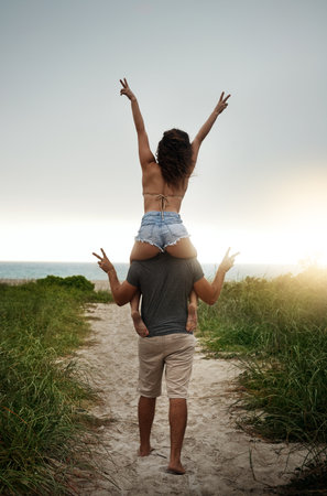 Love gives life meaning. Rearview shot of a happy young couple having fun at the beach.の写真素材