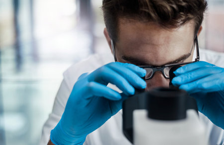 Great discoveries are made everyday. a young male scientist working in a lab with a microscope.の写真素材