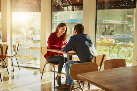 Their first date was going swimmingly well. a young man and woman on a romantic date at a coffee shop.の写真素材