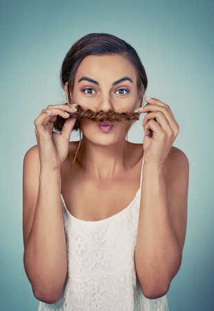 Plaits also make for great moustaches. Studio shot of a beautiful young woman posing against a green background.の写真素材