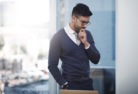 A young businessman looking thoughtful in an office.