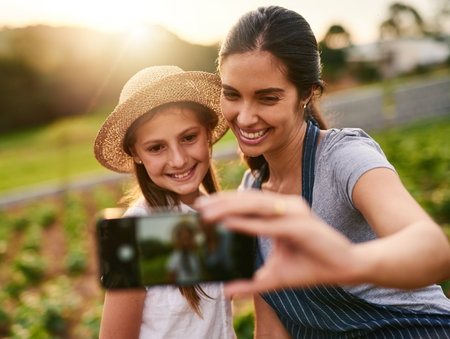 Smile. an attractive young woman and her daughter taking selfies while working on their family farm.の写真素材