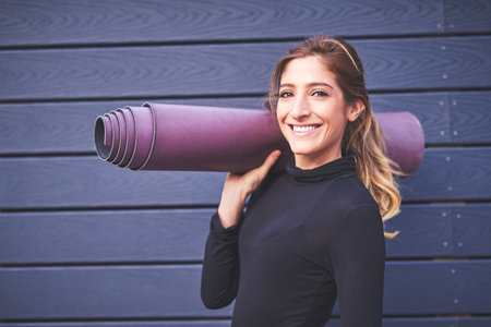Cropped portrait of an attractive young female athlete carrying her yoga mat.
