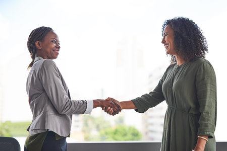Congratulations you got the job. businesswomen shaking hands in the office.の写真素材