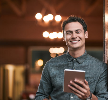 Happy to be part of this business. a confident young man browsing on a digital tablet while standing inside of a beer brewery during the day.の写真素材