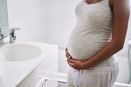 The miracle of holding a new life within. Closeup shot of a pregnant woman standing in the bathroom at home.の写真素材