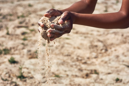 All the moisture has gone. an unrecognizable person holding two hands full of sand showing how dry...