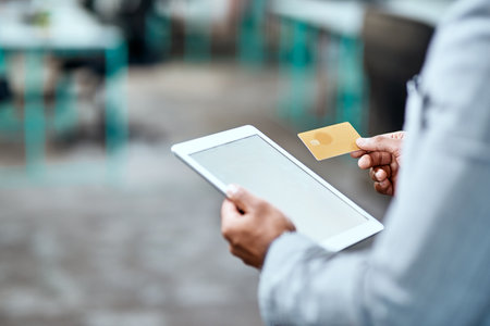 Settle all your business accounts with ease. Closeup shot of an unrecognizable businessman using a credit card and a digital tablet in an office.の写真素材