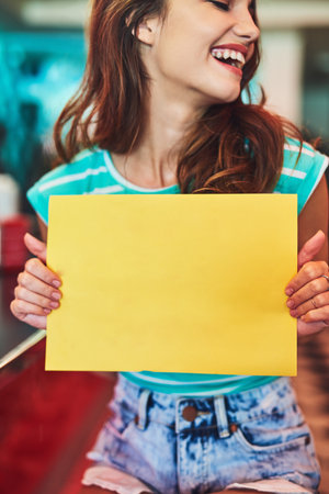 Shes behind this message. an attractive young woman holding up a sign in a retro diner.の写真素材
