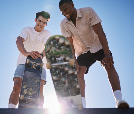 Skateboarder man, friends smile and relax together at skatepark in summer with lens flare outdoor. Black man, friend and skateboard with sports happiness while tired in urban sunshine with diversityの写真素材