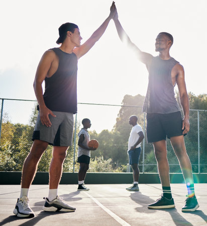 Basketball, high five and teamwork with a sports man friends in celebration as a winner on a court. Fitness, goal or success with a male basketball player and friend celebrating a winning achievementの写真素材