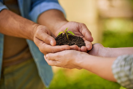 Green is the color of hope. two unidentifiable farmers holding a pile of soil with a seedling growing out of it together.の写真素材