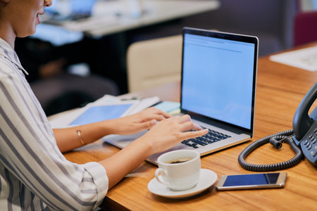 Closeup shot of an unrecognizable businesswoman working on a laptop in an office.の写真素材