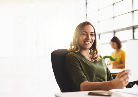 Trust me, I always get the job done. Cropped portrait of an attractive young woman working in a modern office with her colleagues in the background.の写真素材