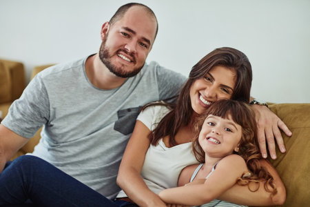The happiest homes have lots of love in them. Portrait of a mother and father bonding with their adorable young daughter at home.の写真素材