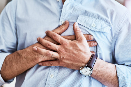 The pain is right here. an unrecognizable man holding his chest while suffering with heartburn at home.の写真素材