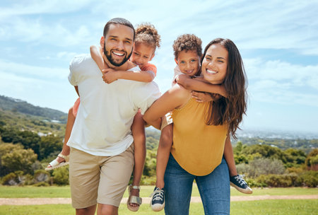 Happy mom, dad and children on piggyback ride from parents in nature park for fun, summer time bonding and outdoor family activity. Black father, mother and kids smile together while playing on grassの写真素材
