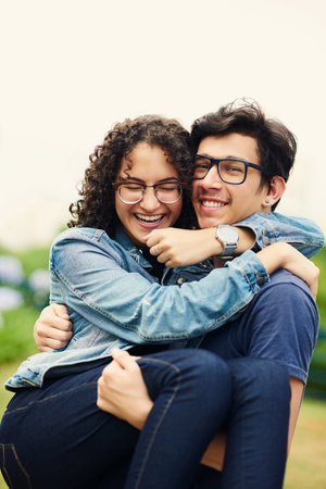Lucky to have found my love so young. a teenage boy carrying his teenage girlfriend outdoors.