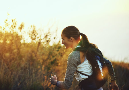 Keeping up with healthy habits. a young woman out for a run along a mountain trail.の写真素材
