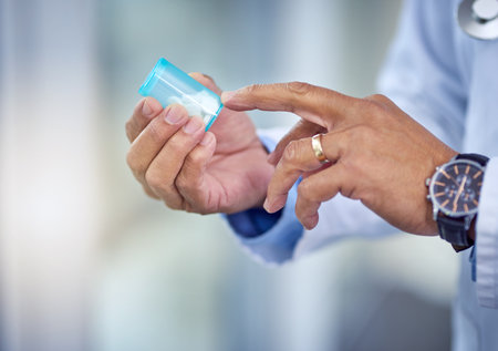 Take a tablet once a day. an unrecognizable male doctors hands holding a pill container inside of a hospital during the day.の写真素材