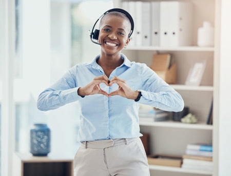 Hand, heart and call center consultant in office showing love, trust and hope while working in crm management. Black woman, hands and thank you while consulting for customer service with excellenceの写真素材