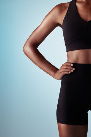 Fitness, body and black woman in studio with workout fashion, skincare and wellness on blue mock up for advertising or marketing space. Sports, runner or athlete zoom in training clothes and mockupの写真素材