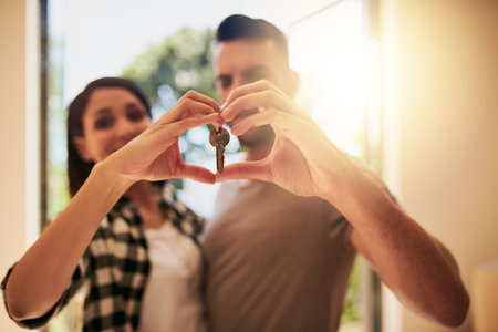 Our home will be filled with so much love. Portrait of a young couple holding the keys to their new home.の写真素材
