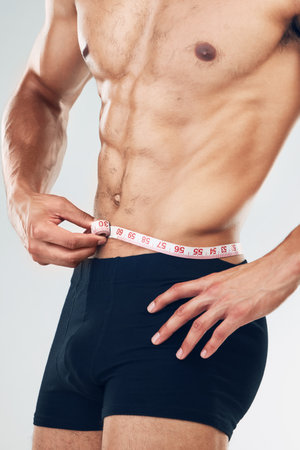 Fitness, lose weight and measuring tape of man to check waist size, progress and diet or workout, exercise and training results. Body motivation of healthy bodybuilder goals for health and wellnessの写真素材