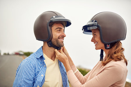 Safety comes first. a woman adjusting her boyfriends helmet.の写真素材